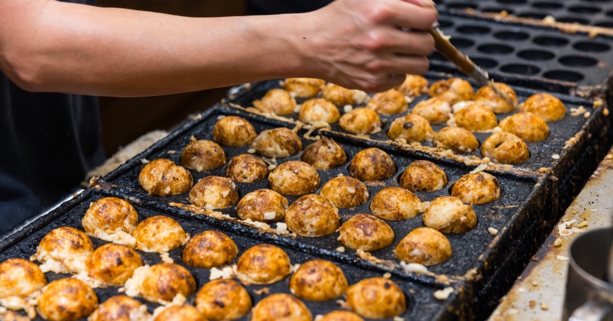 Takoyaki turning on a hot griddle in Osaka