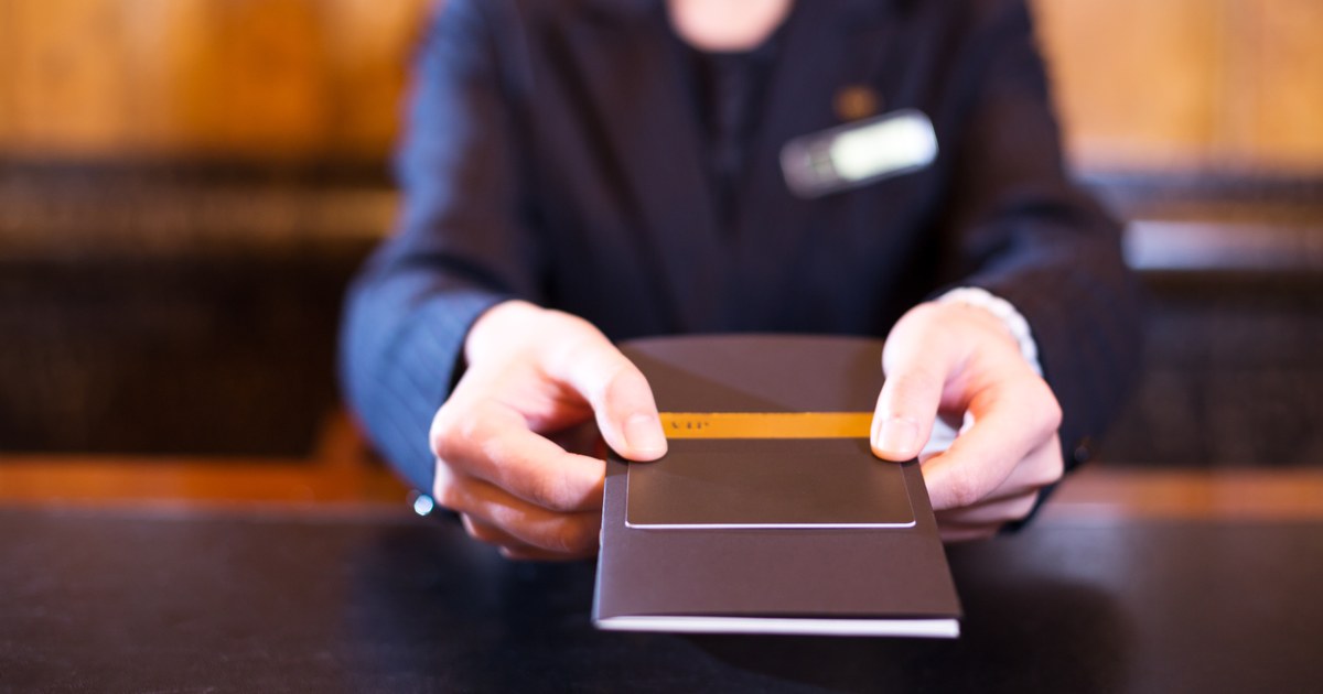 A concierge handing over a room key across the desk