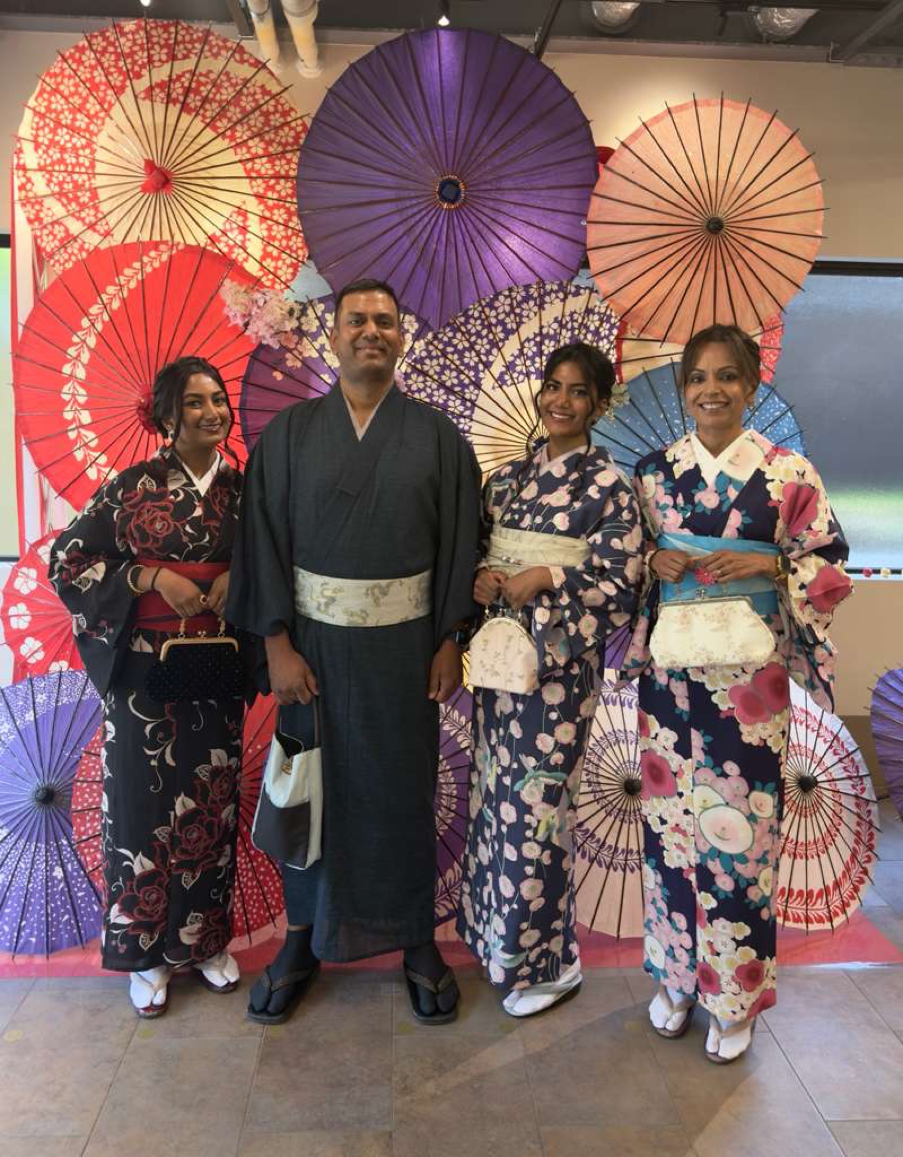 The family in kimono before a wall of paper parasols