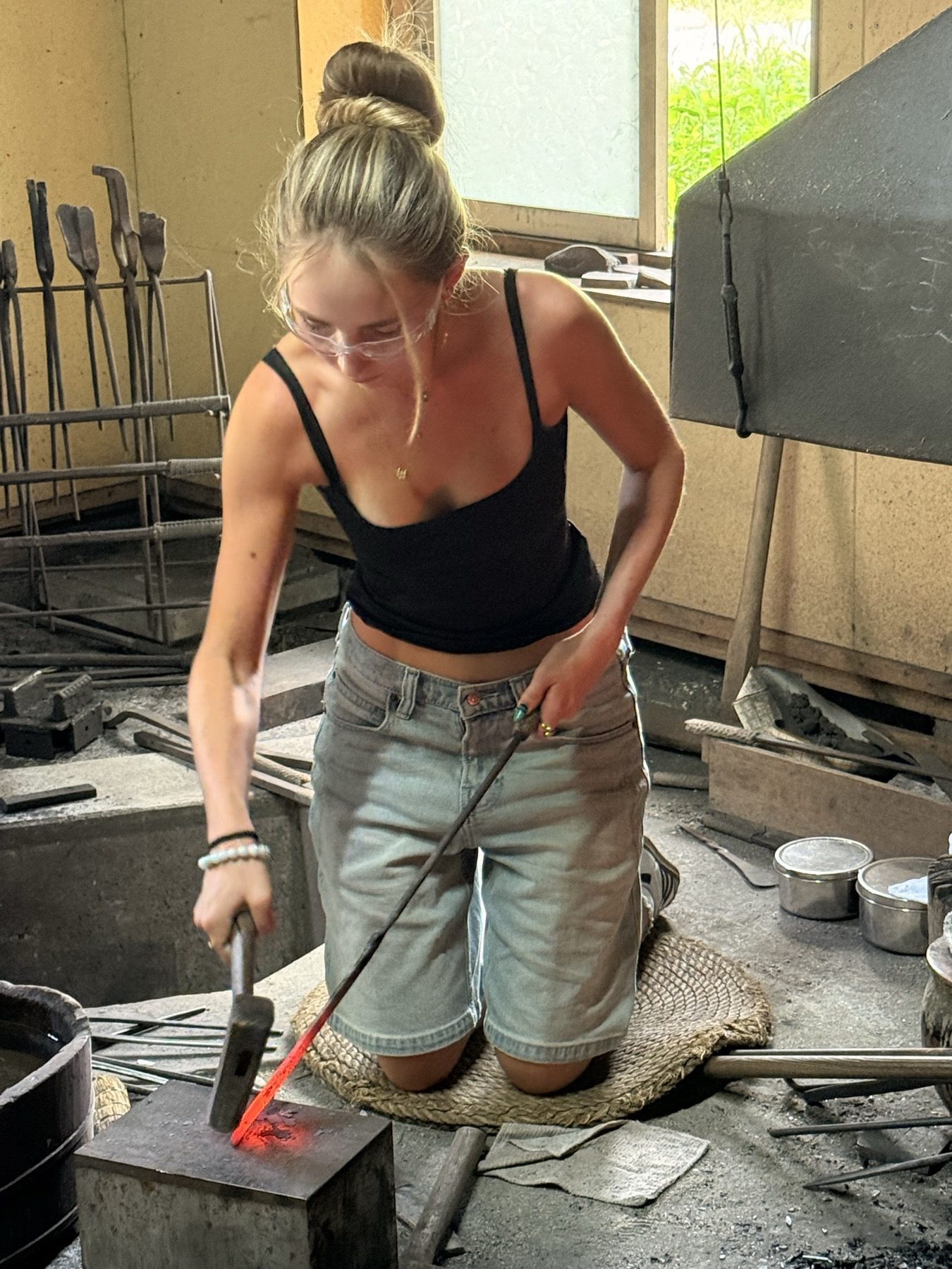 The family's daughter hammering hot steel at a swordsmith's forge